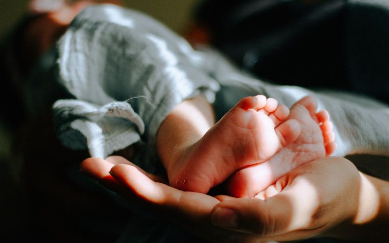 Babyfüße, gehalten in den Händen eines Elternteils